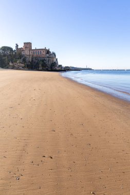 Atlantik 'te gün doğumu, sahilin ortasında bir kale. Limanı koruyan tarihi bir bina. Castelo de Ferragudo, kumlu Praia da Angrinha sahilinde, Portimo, Algarve, Portekiz