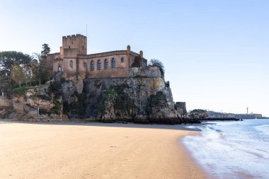 Atlantik 'te gün doğumu, sahilin ortasında bir kale. Limanı koruyan tarihi bir bina. Castelo de Ferragudo, kumlu Praia da Angrinha sahilinde, Portimo, Algarve, Portekiz