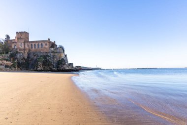 Atlantik 'te gün doğumu, sahilin ortasında bir kale. Limanı koruyan tarihi bir bina. Castelo de Ferragudo, kumlu Praia da Angrinha sahilinde, Portimo, Algarve, Portekiz