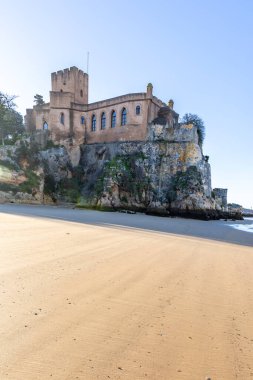 Atlantik 'te gün doğumu, sahilin ortasında bir kale. Limanı koruyan tarihi bir bina. Castelo de Ferragudo, kumlu Praia da Angrinha sahilinde, Portimo, Algarve, Portekiz
