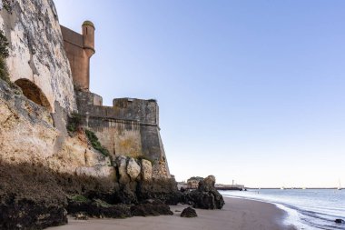 Atlantik 'te gün doğumu, sahilin ortasında bir kale. Limanı koruyan tarihi bir bina. Castelo de Ferragudo, kumlu Praia da Angrinha sahilinde, Portimo, Algarve, Portekiz