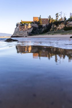Atlantik 'te gün doğumu, sahilin ortasında bir kale. Limanı koruyan tarihi bir bina. Castelo de Ferragudo, kumlu Praia da Angrinha sahilinde, Portimo, Algarve, Portekiz