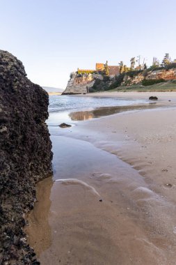 Atlantik 'te gün doğumu, sahilin ortasında bir kale. Limanı koruyan tarihi bir bina. Castelo de Ferragudo, kumlu Praia da Angrinha sahilinde, Portimo, Algarve, Portekiz