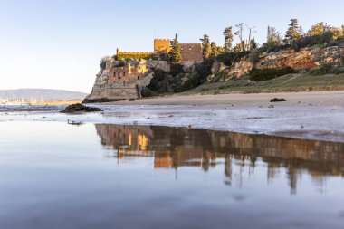 Atlantik 'te gün doğumu, sahilin ortasında bir kale. Limanı koruyan tarihi bir bina. Castelo de Ferragudo, kumlu Praia da Angrinha sahilinde, Portimo, Algarve, Portekiz