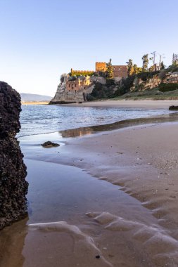 Atlantik 'te gün doğumu, sahilin ortasında bir kale. Limanı koruyan tarihi bir bina. Castelo de Ferragudo, kumlu Praia da Angrinha sahilinde, Portimo, Algarve, Portekiz