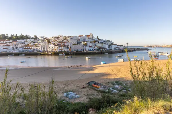Güneşin doğuşu çayıra, kumlu plaja ve alçak gelgitte limana bakıyor. Günbatımında Ferragudo, Portimo, Algarve, Portekiz 'de tarihi bir kasabanın panoramik manzarası