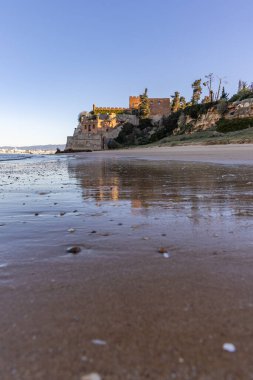 Atlantik 'te gün doğumu, sahilin ortasında bir kale. Limanı koruyan tarihi bir bina. Castelo de Ferragudo, kumlu Praia da Angrinha sahilinde, Portimo, Algarve, Portekiz