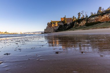 Atlantik 'te gün doğumu, sahilin ortasında bir kale. Limanı koruyan tarihi bir bina. Castelo de Ferragudo, kumlu Praia da Angrinha sahilinde, Portimo, Algarve, Portekiz