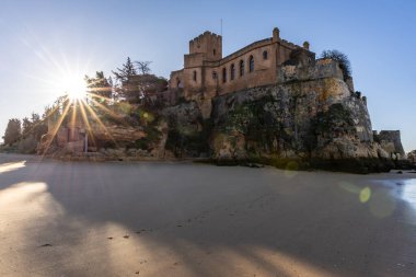 Atlantik 'te gün doğumu, sahilin ortasında bir kale. Limanı koruyan tarihi bir bina. Castelo de Ferragudo, kumlu Praia da Angrinha sahilinde, Portimo, Algarve, Portekiz