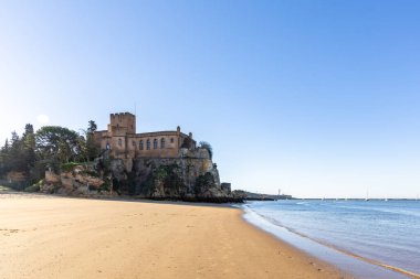 Atlantik 'te gün doğumu, sahilin ortasında bir kale. Limanı koruyan tarihi bir bina. Castelo de Ferragudo, kumlu Praia da Angrinha sahilinde, Portimo, Algarve, Portekiz