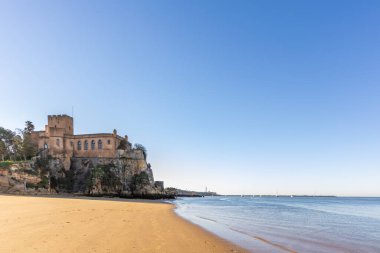 Atlantik 'te gün doğumu, sahilin ortasında bir kale. Limanı koruyan tarihi bir bina. Castelo de Ferragudo, kumlu Praia da Angrinha sahilinde, Portimo, Algarve, Portekiz