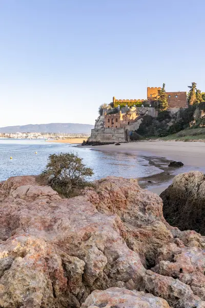 Atlantik 'te gün doğumu, sahilin ortasında bir kale. Limanı koruyan tarihi bir bina. Castelo de Ferragudo, kumlu Praia da Angrinha sahilinde, Portimo, Algarve, Portekiz
