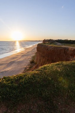 Atlantik 'in sakin sularında, gelgitte yansımaları olan deniz. Praia do Poo Velho, Praia da Falsia, Quarteira, Algarve, Portekiz uçurumlarındaki gün batımının manzarası.