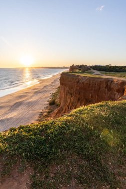 Atlantik 'in sakin sularında, gelgitte yansımaları olan deniz. Praia do Poo Velho, Praia da Falsia, Quarteira, Algarve, Portekiz uçurumlarındaki gün batımının manzarası.