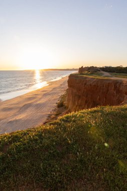 Atlantik 'in sakin sularında, gelgitte yansımaları olan deniz. Praia do Poo Velho, Praia da Falsia, Quarteira, Algarve, Portekiz uçurumlarındaki gün batımının manzarası.