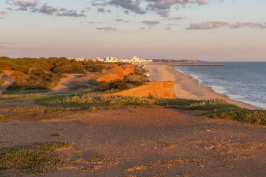 Atlantik 'in sakin sularında, gelgitte yansımaları olan deniz. Praia do Poo Velho, Praia da Falsia, Quarteira, Algarve, Portekiz uçurumlarındaki gün batımının manzarası.