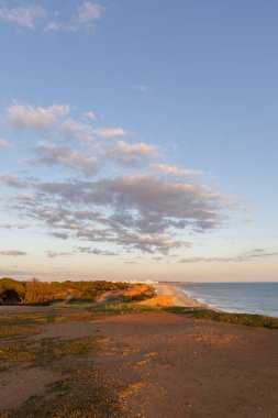 Atlantik 'in sakin sularında, gelgitte yansımaları olan deniz. Praia do Poo Velho, Praia da Falsia, Quarteira, Algarve, Portekiz uçurumlarındaki gün batımının manzarası.