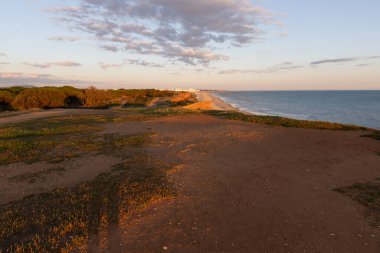 Atlantik 'in sakin sularında, gelgitte yansımaları olan deniz. Praia do Poo Velho, Praia da Falsia, Quarteira, Algarve, Portekiz uçurumlarındaki gün batımının manzarası.