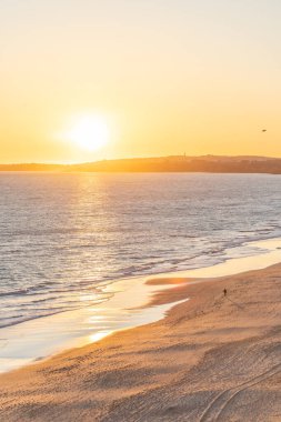 Atlantik 'in sakin sularında, gelgitte yansımaları olan deniz. Praia do Poo Velho, Praia da Falsia, Quarteira, Algarve, Portekiz uçurumlarındaki gün batımının manzarası.