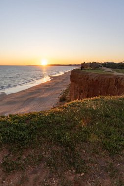 Atlantik 'in sakin sularında, gelgitte yansımaları olan deniz. Praia do Poo Velho, Praia da Falsia, Quarteira, Algarve, Portekiz uçurumlarındaki gün batımının manzarası.
