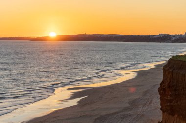 Atlantik 'in sakin sularında deniz akıntısı azalıyor. Praia do Poo Velho, Praia da Falsia, Quarteira, Algarve, Portekiz uçurumlarındaki gün batımının manzarası.