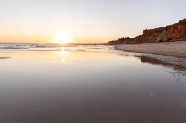 Atlantik 'in sakin sularında deniz akıntısı azalıyor. Praia do Poo Velho, Praia da Falsia, Quarteira, Algarve, Portekiz uçurumlarındaki gün batımının manzarası.