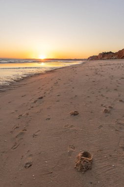 Atlantik 'te kumlu bir sahil. Kum taşı kayalıkları olan bir sahilin gün batımında manzara. Albufeira, Algarve, Portekiz yakınlarındaki Praia da Falsia 'nın sarı sahilinde gelgit var.