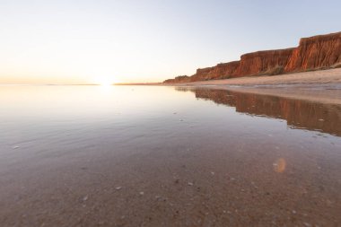 Atlantik 'in sakin sularında deniz akıntısı azalıyor. Praia do Poo Velho, Praia da Falsia, Quarteira, Algarve, Portekiz uçurumlarındaki gün batımının manzarası.