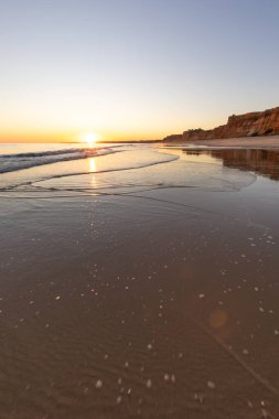 Atlantik 'in sakin sularında deniz akıntısı azalıyor. Praia do Poo Velho, Praia da Falsia, Quarteira, Algarve, Portekiz uçurumlarındaki gün batımının manzarası.