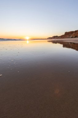 Atlantik 'in sakin sularında deniz akıntısı azalıyor. Praia do Poo Velho, Praia da Falsia, Quarteira, Algarve, Portekiz uçurumlarındaki gün batımının manzarası.