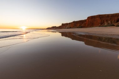 Atlantik 'in sakin sularında deniz akıntısı azalıyor. Praia do Poo Velho, Praia da Falsia, Quarteira, Algarve, Portekiz uçurumlarındaki gün batımının manzarası.