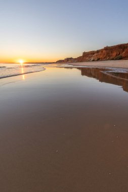 Atlantik 'in sakin sularında deniz akıntısı azalıyor. Praia do Poo Velho, Praia da Falsia, Quarteira, Algarve, Portekiz uçurumlarındaki gün batımının manzarası.