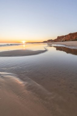 Atlantik 'in sakin sularında deniz akıntısı azalıyor. Praia do Poo Velho, Praia da Falsia, Quarteira, Algarve, Portekiz uçurumlarındaki gün batımının manzarası.
