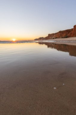 Atlantik 'in sakin sularında deniz akıntısı azalıyor. Praia do Poo Velho, Praia da Falsia, Quarteira, Algarve, Portekiz uçurumlarındaki gün batımının manzarası.