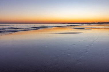Atlantik 'in sakin sularında deniz akıntısı azalıyor. Praia do Poo Velho, Praia da Falsia, Quarteira, Algarve, Portekiz uçurumlarındaki gün batımının manzarası.