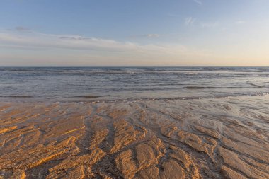 Atlantik 'te kumlu bir sahil. Kum taşı kayalıkları olan bir sahilin gün batımında manzara. Albufeira, Algarve, Portekiz yakınlarındaki Praia da Falsia 'nın sarı sahilinde gelgit var.