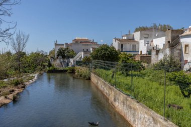 Çitlerle çevrili bir bahar, bazen yüzme havuzuna dönüşen tarihi bir yer. Praia Fluvial de Alte 'nin eski duvarları, Algarve, Portekiz