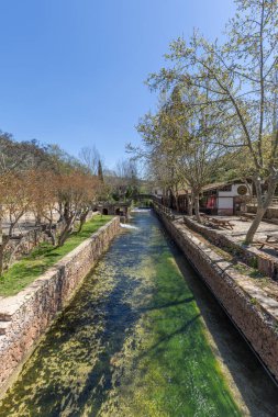Çitlerle çevrili bir bahar, bazen yüzme havuzuna dönüşen tarihi bir yer. Praia Fluvial de Alte 'nin eski duvarları, Algarve, Portekiz