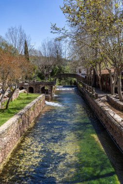 Çitlerle çevrili bir bahar, bazen yüzme havuzuna dönüşen tarihi bir yer. Praia Fluvial de Alte 'nin eski duvarları, Algarve, Portekiz