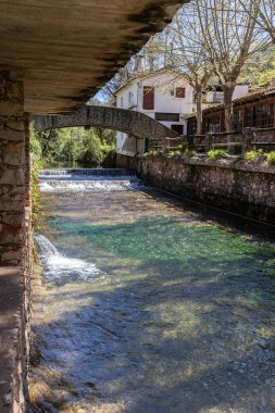 Çitlerle çevrili bir bahar, bazen yüzme havuzuna dönüşen tarihi bir yer. Praia Fluvial de Alte 'nin eski duvarları, Algarve, Portekiz