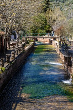 Çitlerle çevrili bir bahar, bazen yüzme havuzuna dönüşen tarihi bir yer. Praia Fluvial de Alte 'nin eski duvarları, Algarve, Portekiz
