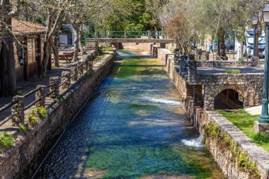 Çitlerle çevrili bir bahar, bazen yüzme havuzuna dönüşen tarihi bir yer. Praia Fluvial de Alte 'nin eski duvarları, Algarve, Portekiz