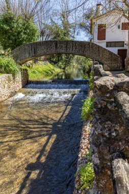 Çitlerle çevrili bir bahar, bazen yüzme havuzuna dönüşen tarihi bir yer. Praia Fluvial de Alte 'nin eski duvarları, Algarve, Portekiz