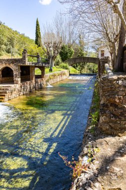 Çitlerle çevrili bir bahar, bazen yüzme havuzuna dönüşen tarihi bir yer. Praia Fluvial de Alte 'nin eski duvarları, Algarve, Portekiz