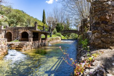 Çitlerle çevrili bir bahar, bazen yüzme havuzuna dönüşen tarihi bir yer. Praia Fluvial de Alte 'nin eski duvarları, Algarve, Portekiz