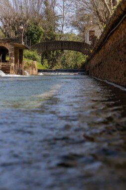 Çitlerle çevrili bir bahar, bazen yüzme havuzuna dönüşen tarihi bir yer. Praia Fluvial de Alte 'nin eski duvarları, Algarve, Portekiz