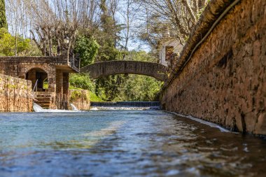 Çitlerle çevrili bir bahar, bazen yüzme havuzuna dönüşen tarihi bir yer. Praia Fluvial de Alte 'nin eski duvarları, Algarve, Portekiz
