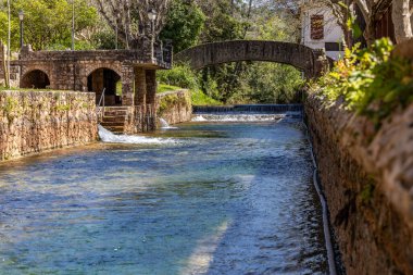 Çitlerle çevrili bir bahar, bazen yüzme havuzuna dönüşen tarihi bir yer. Praia Fluvial de Alte 'nin eski duvarları, Algarve, Portekiz