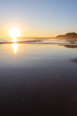 Alçak gelgitte kumlu bir sahil manzarası. Gün batımında etrafındaki kayalar ve kayalıklar denize yansıyor. Praia da Falsia, Algarve, Portekiz