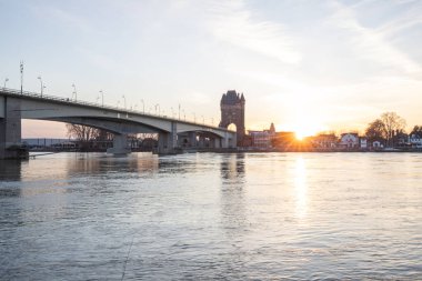 Eski tarihi bir şehir kapısından bir yol ya da otoyol geçiyor. Solucanlar, Almanya yakınlarındaki Ren nehrinde akşam üstü gün batımı